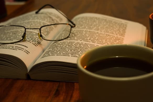 Un libro abierto, unos lentes y una taza de café