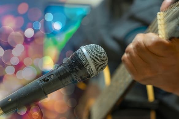 Un micrófono y una persona tocando un instrumento de cuerda