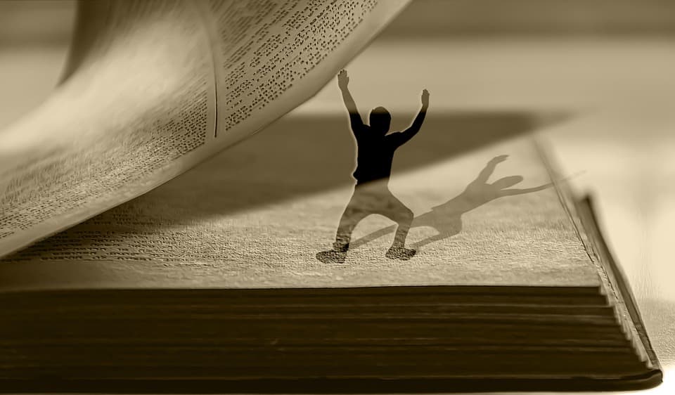 Una pequeña figura de sombras sosteniendo una página de un libro abierto