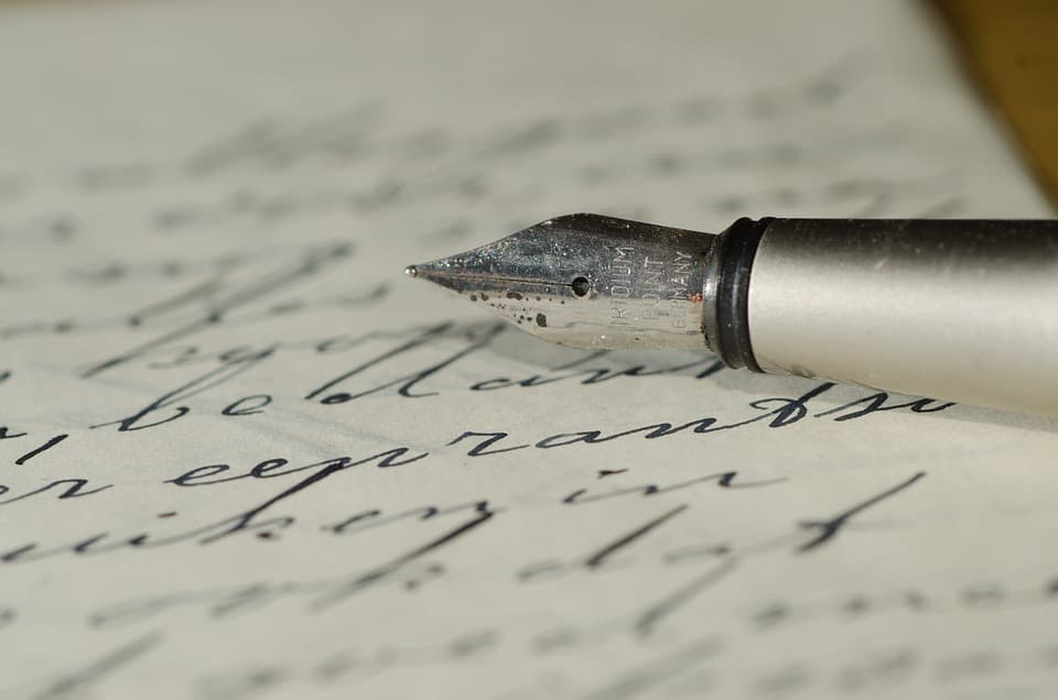 Un papel escrito en cursiva y una pluma